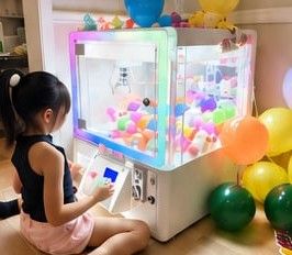 A young girl playing a light-up claw machine at a birthday party